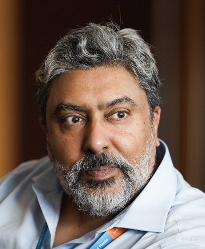 Middle-aged man in a doctor's coat looking directly at the camera.