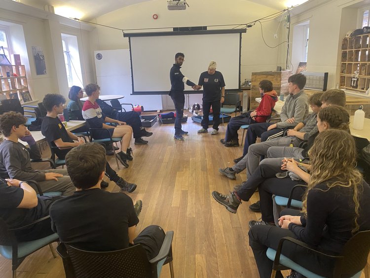 Indoor group session with an emergency responder demonstrating equipment to an attentive audience.