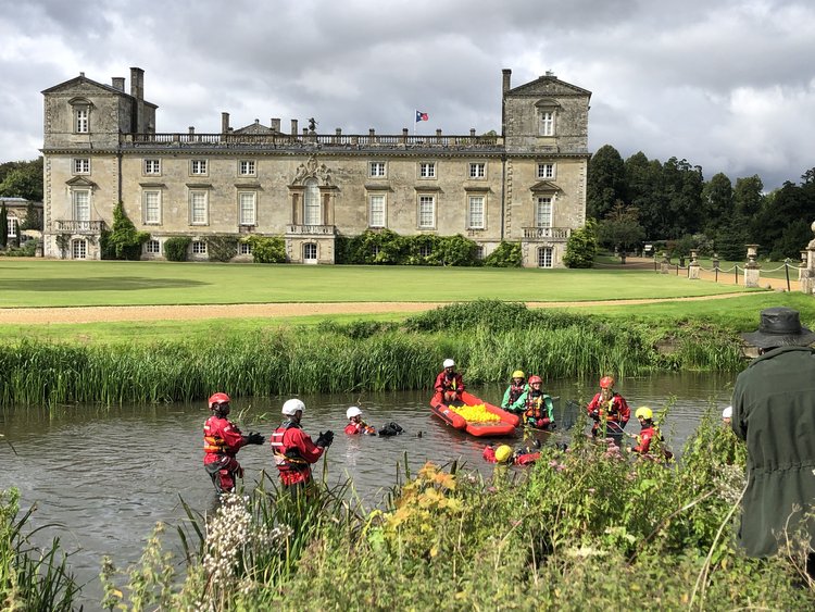 Rescue team in water performing a drill with a castle-like building in the background.