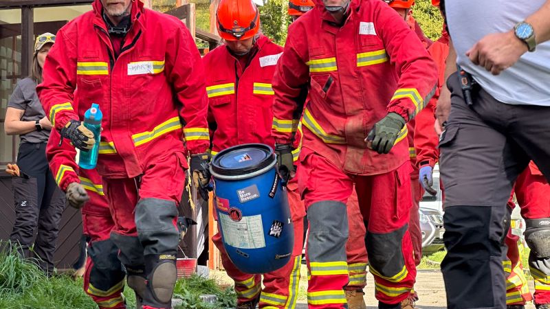 Rescue workers transporting a hazardous material drum during a training exercise.