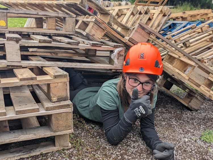 Rescue worker crawling under a wooden structure during a search and rescue exercise.