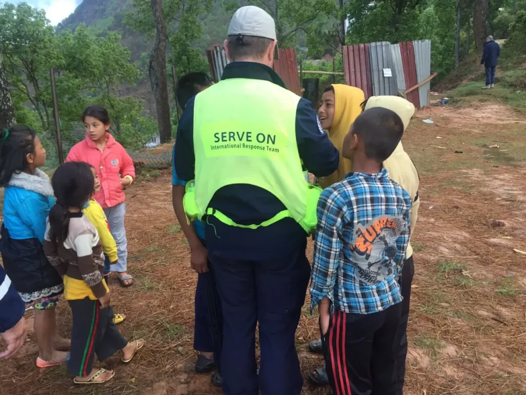 A rescue team member engaging with local children in a rural setting.